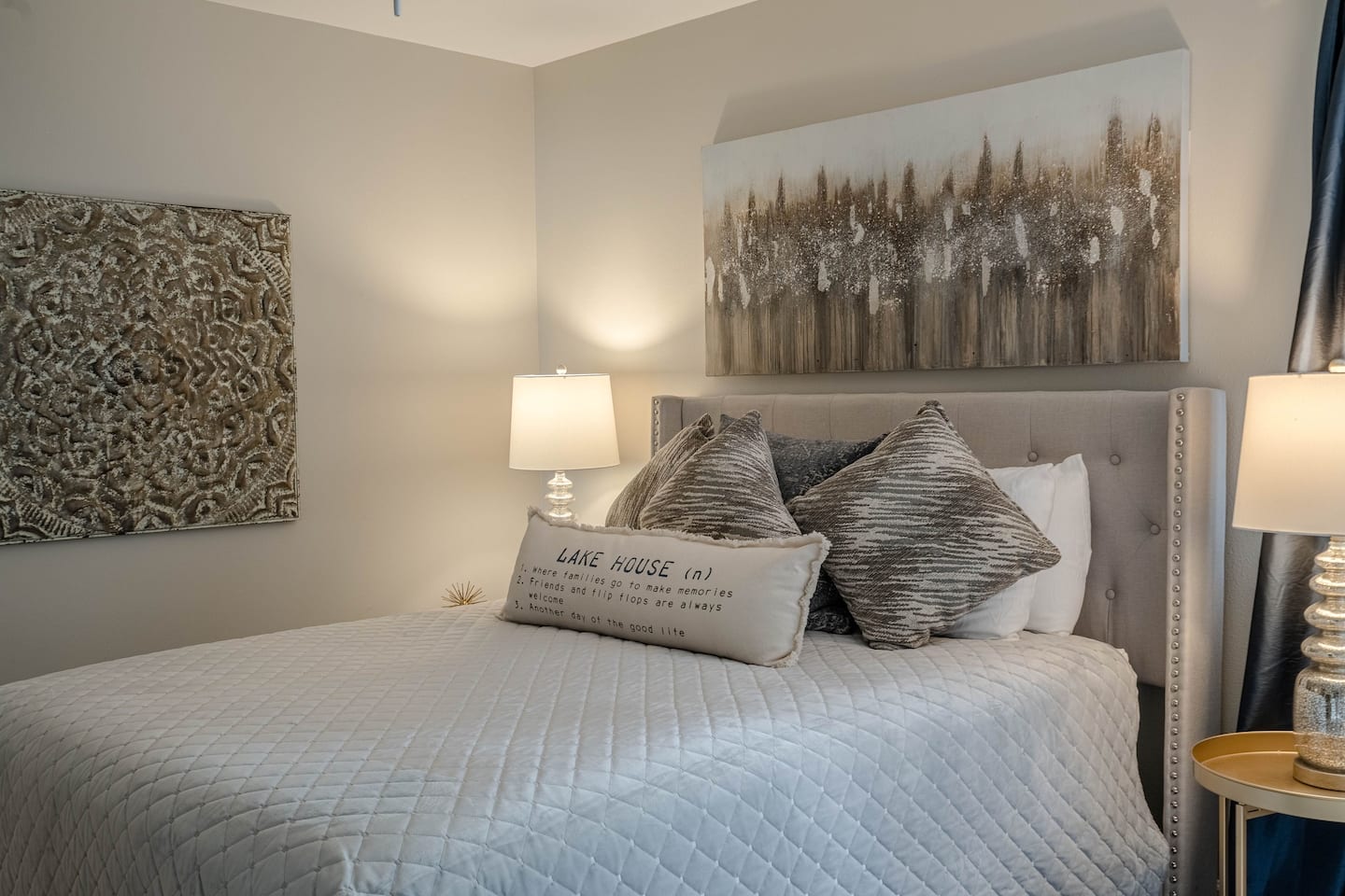 A bedroom with a bed , lamps , and a painting on the wall.