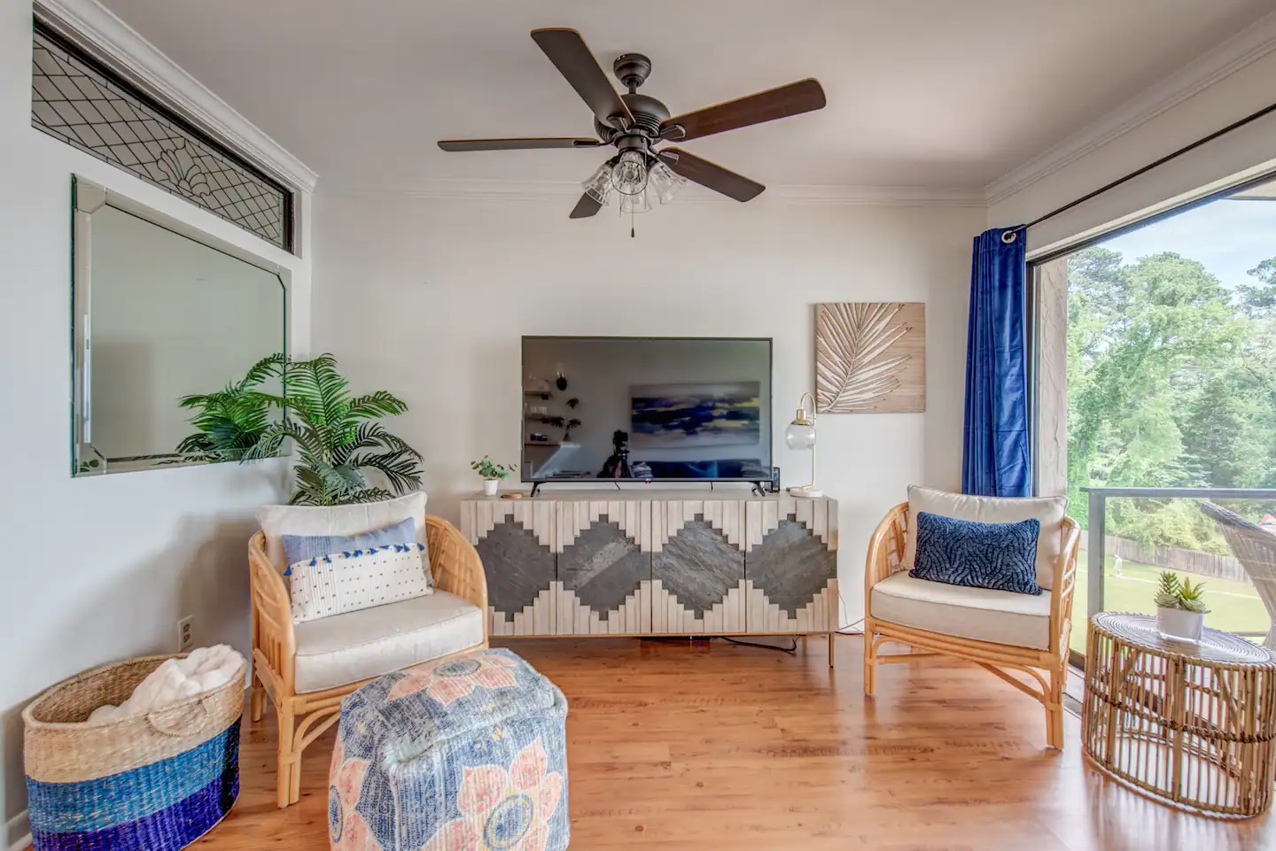A living room with a ceiling fan and a flat screen tv.