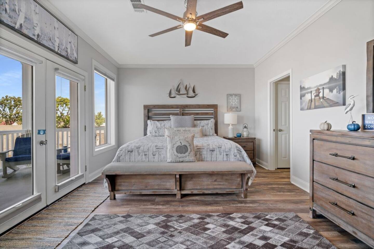 A bedroom with a king size bed , dresser , rug and ceiling fan.