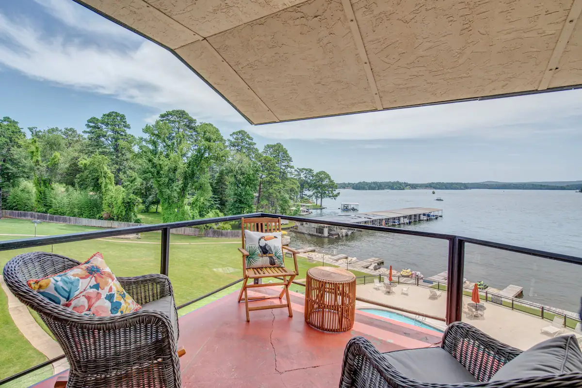 A balcony with two chairs and a table overlooking a lake.