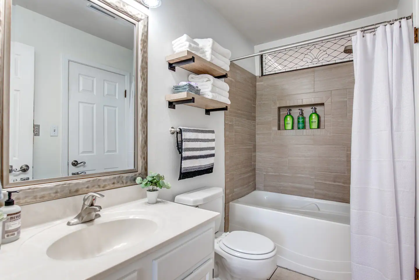 A bathroom with a sink , toilet , tub and mirror.