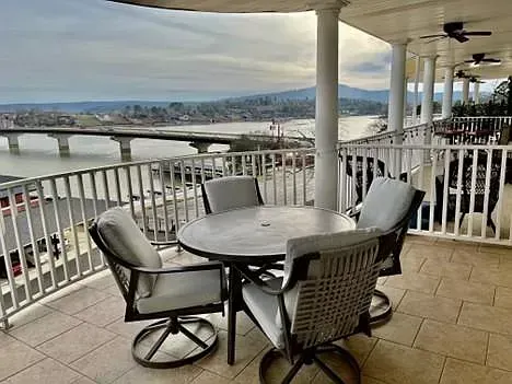 A balcony with a table and chairs overlooking a body of water.