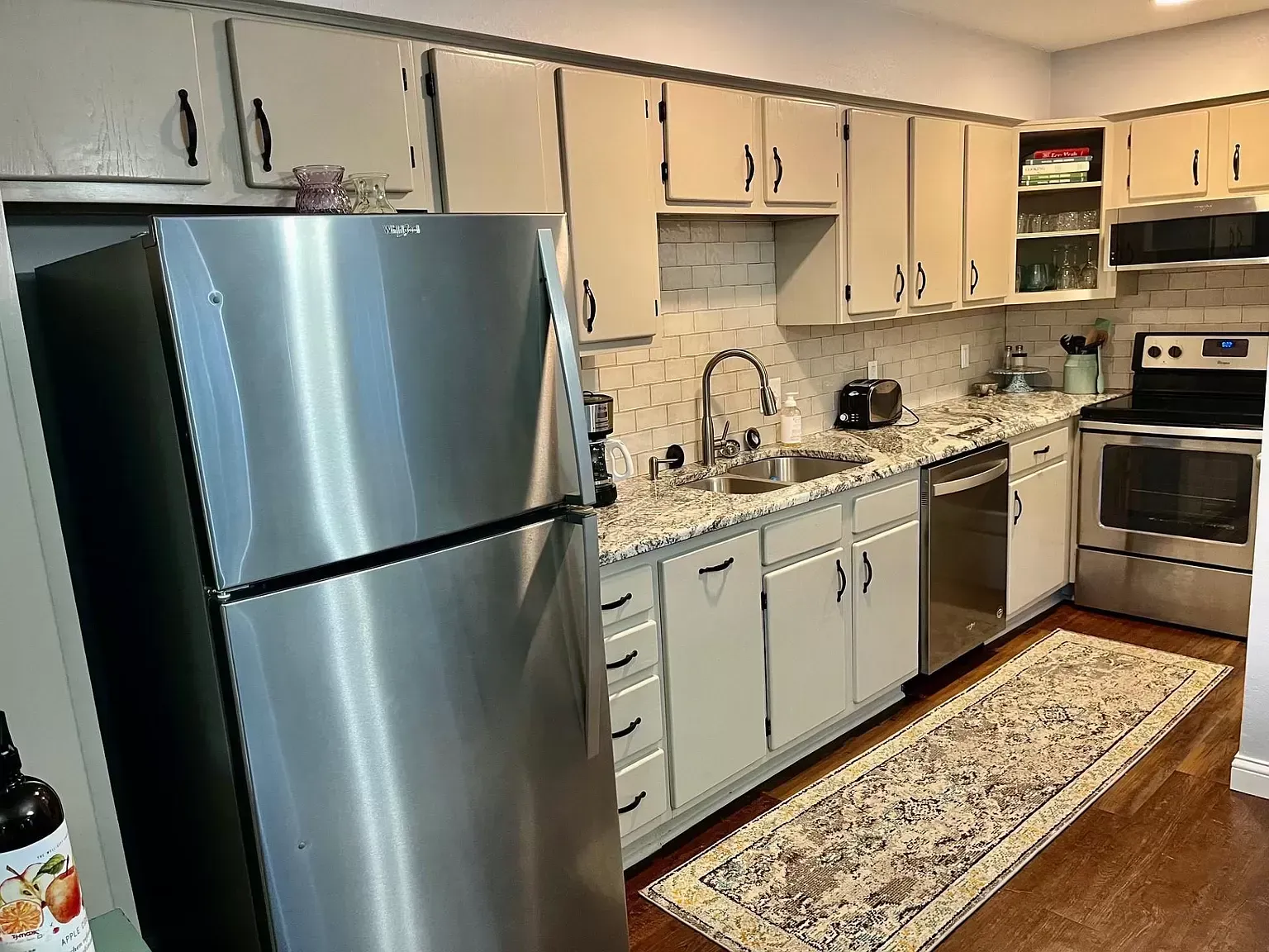 A kitchen with stainless steel appliances and white cabinets.