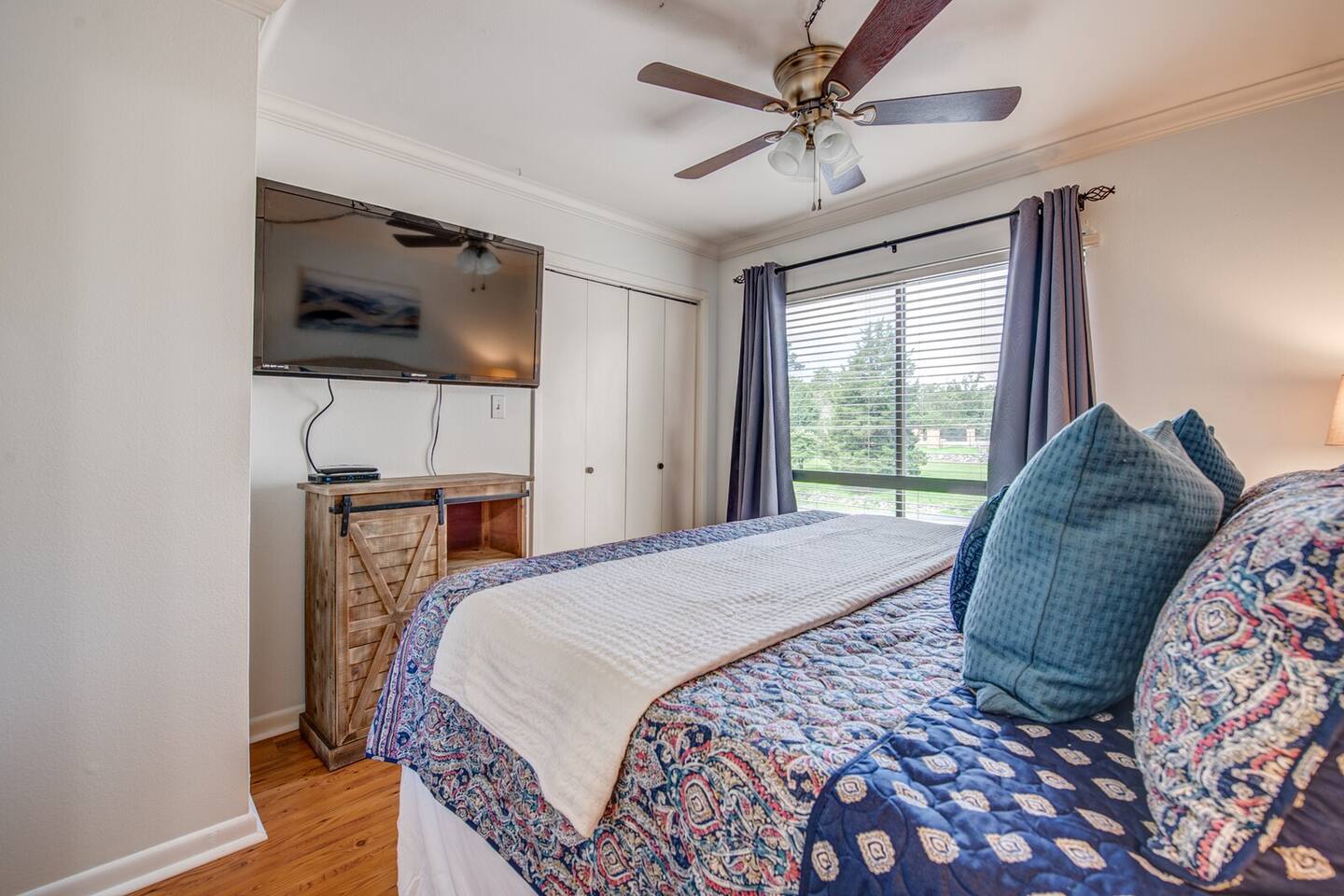 A bedroom with a king size bed , television , and ceiling fan.