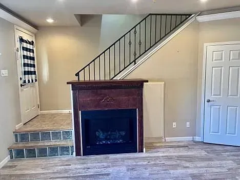A living room with a fireplace and stairs in a house.