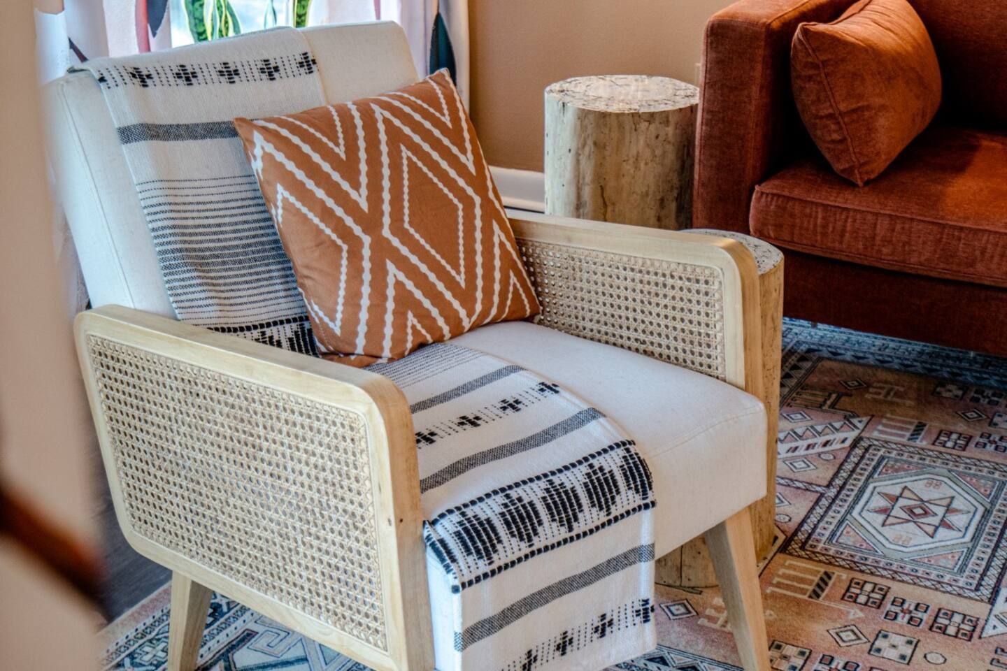 A chair with a blanket on it is sitting in a living room next to a couch.