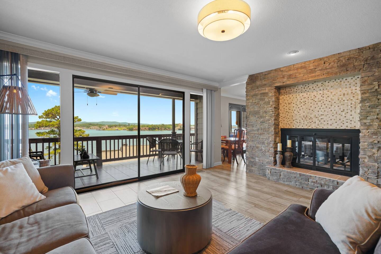 A living room with a couch , table and fireplace with a view of a lake.