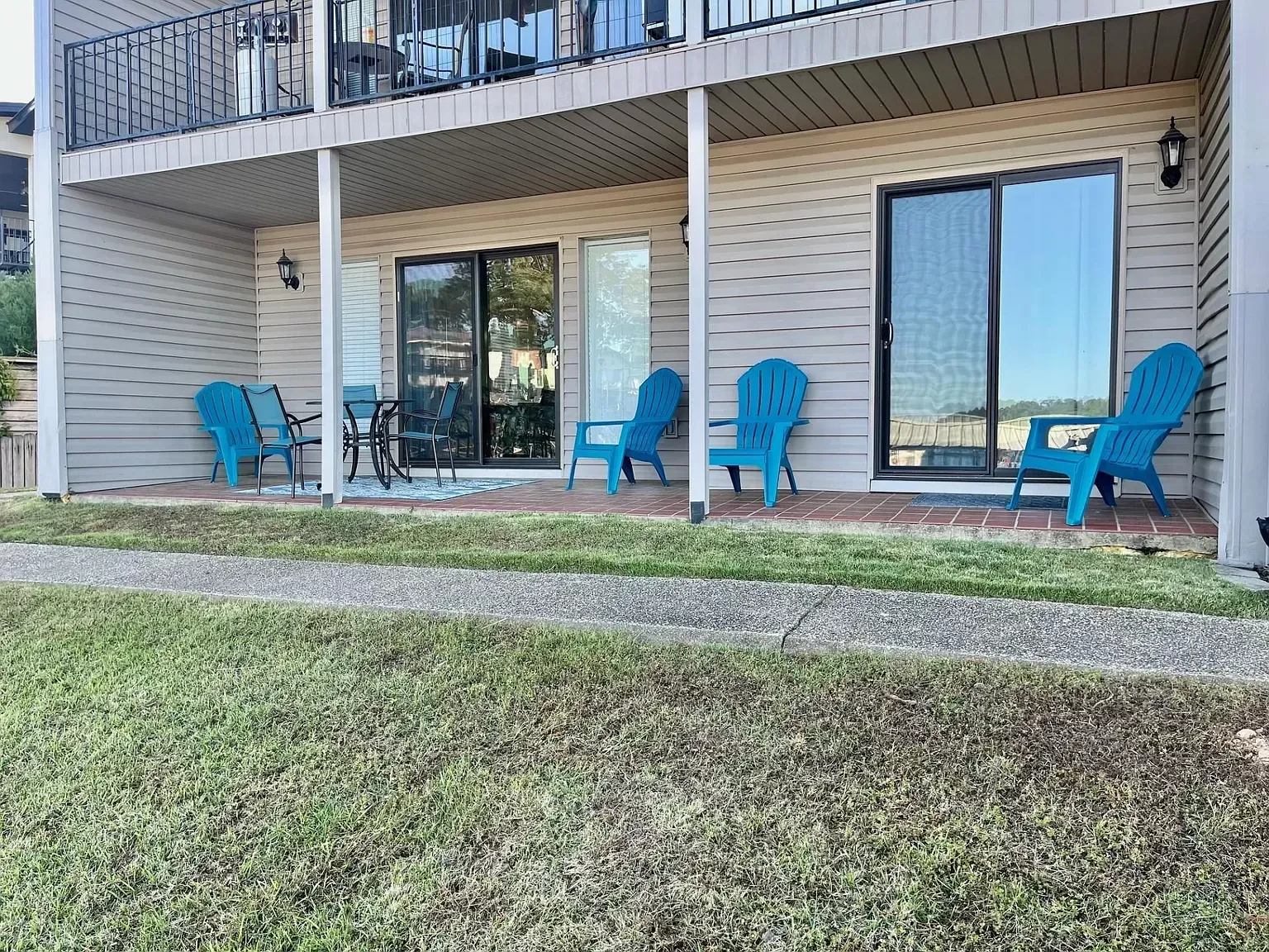 A patio with blue chairs and a table in front of a house.
