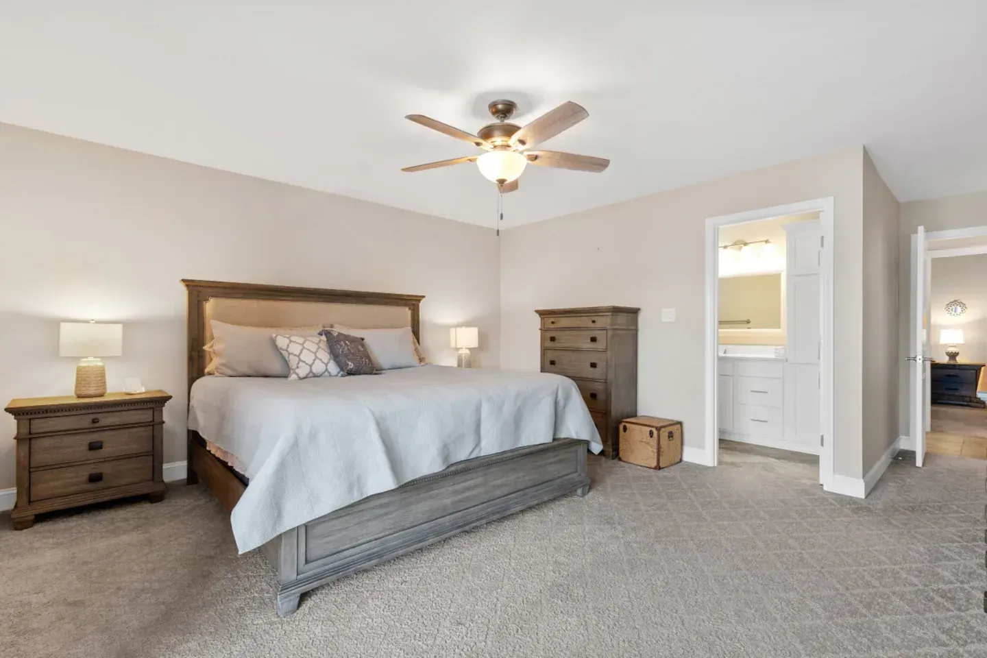 A bedroom with a bed , nightstand , dresser and ceiling fan.