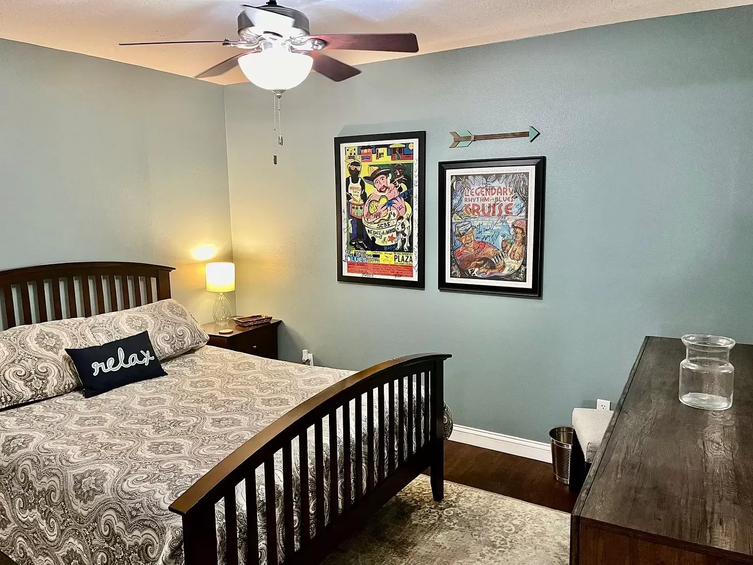 A bedroom with a bed , dresser , and ceiling fan.