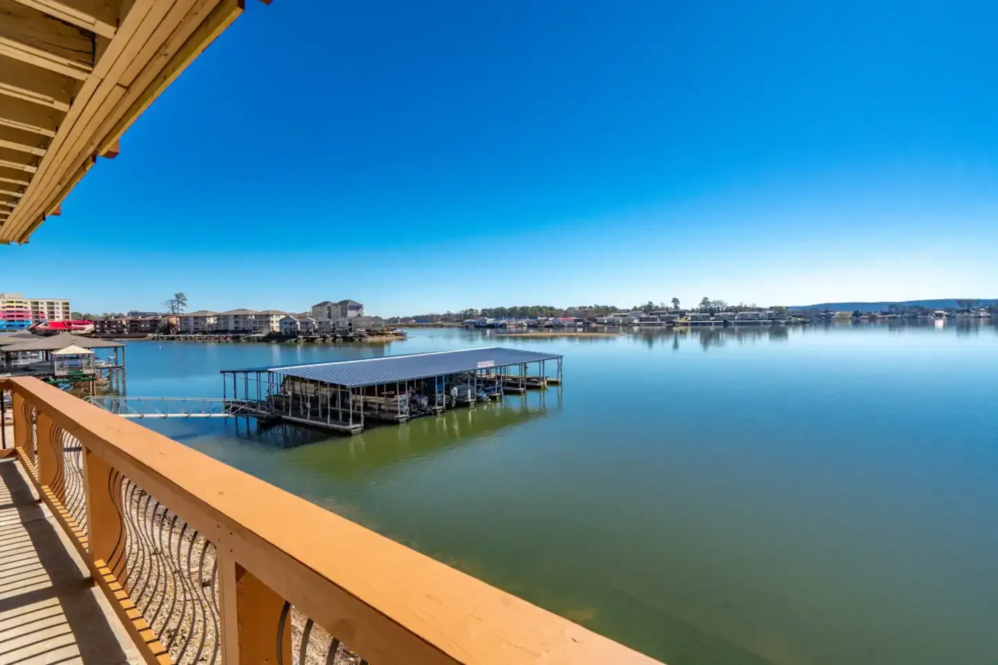 A view of a lake from a balcony with boats docked in the water.
