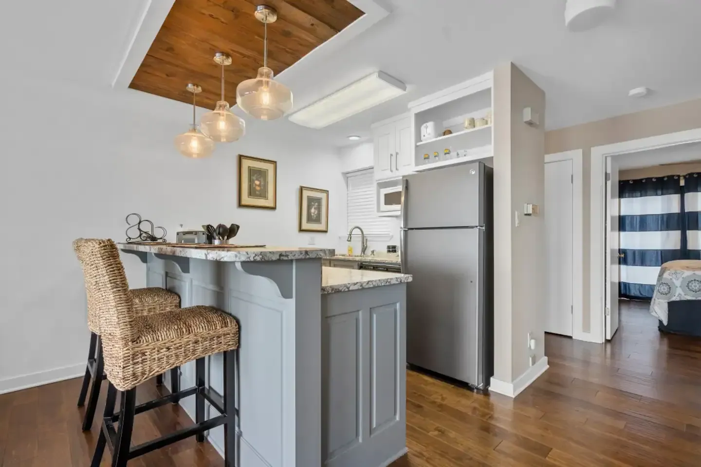 A kitchen with a stainless steel refrigerator and a bar with wicker chairs.