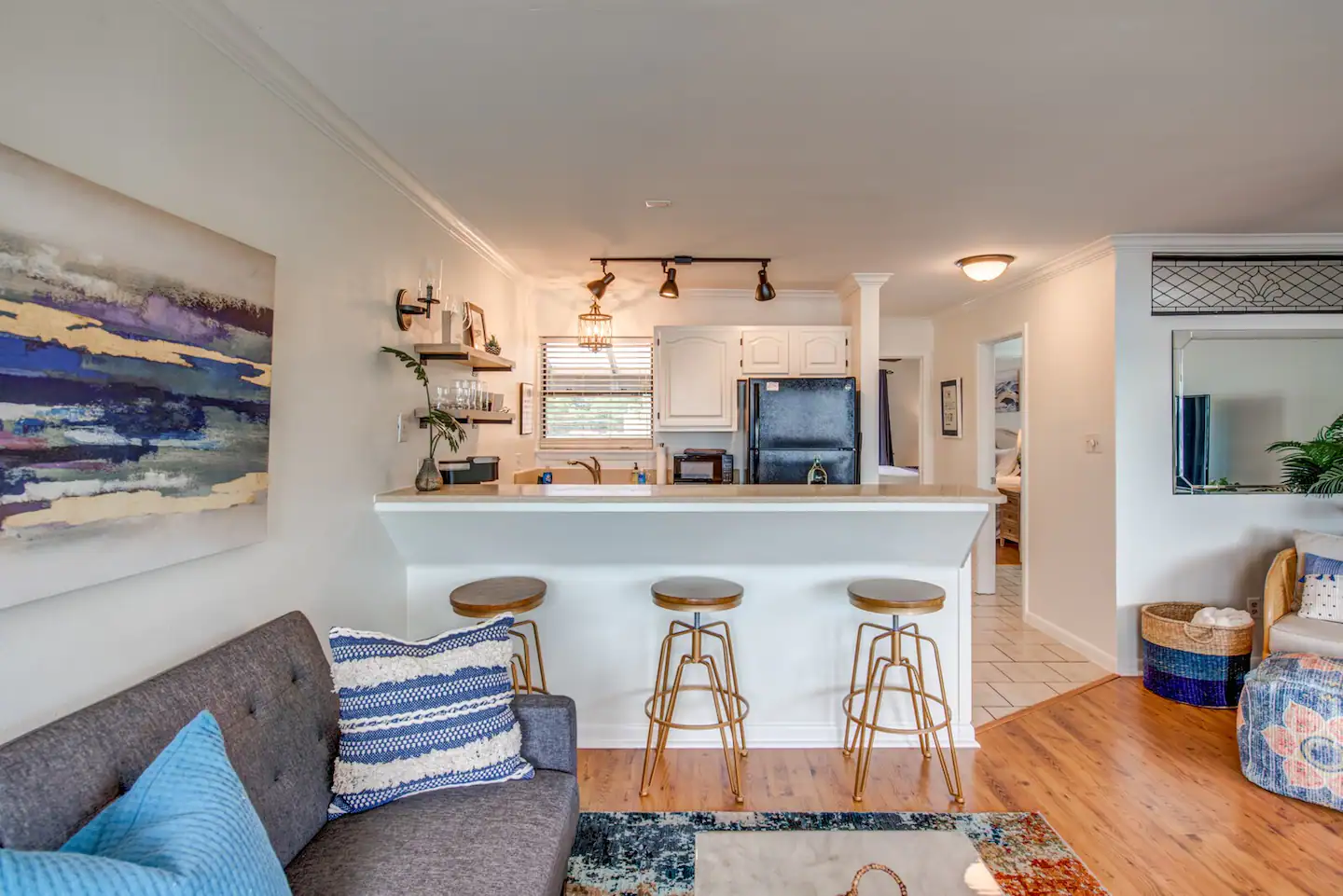 A living room with a couch and stools and a kitchen in the background.