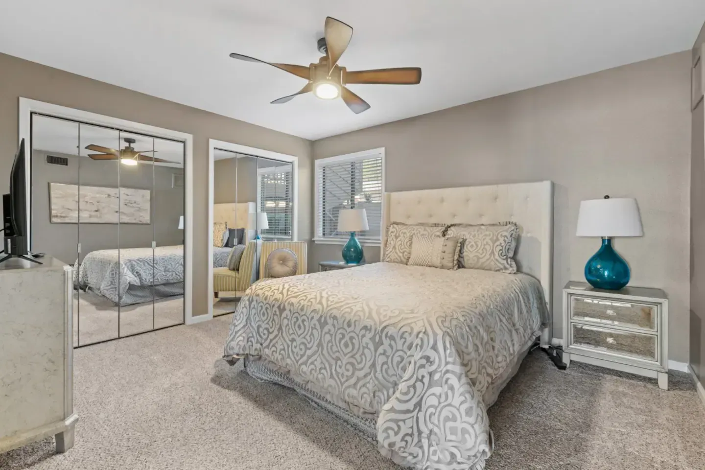 A bedroom with a large bed and a ceiling fan.
