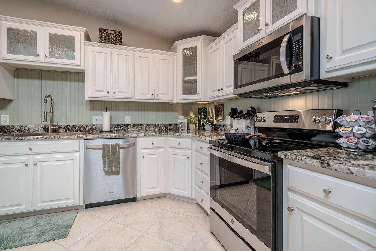 A kitchen with white cabinets , stainless steel appliances and granite counter tops.
