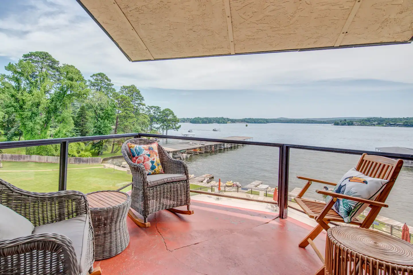 A balcony with rocking chairs and tables overlooking a body of water.