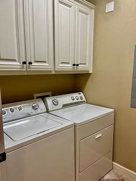 A laundry room with a washer and dryer and white cabinets.