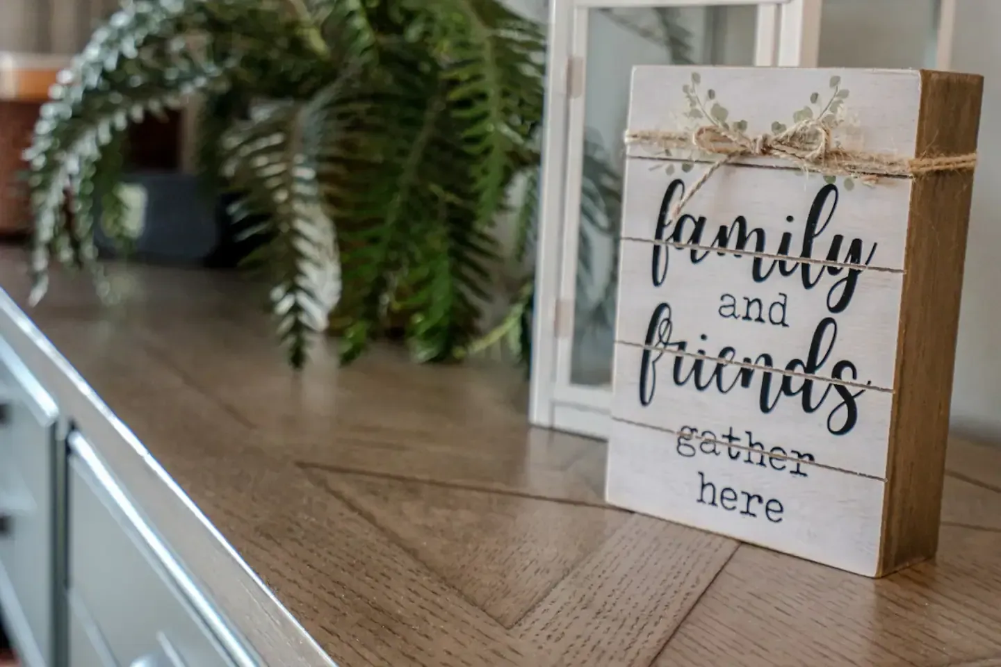 A wooden sign that says `` family and friends gather here '' is sitting on a wooden table.