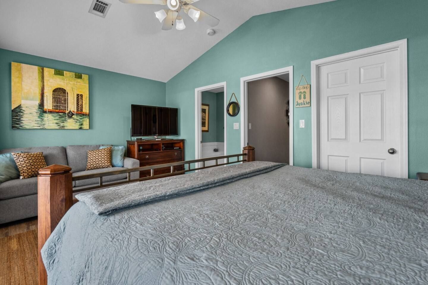 A bedroom with a bed , couch , television and ceiling fan.