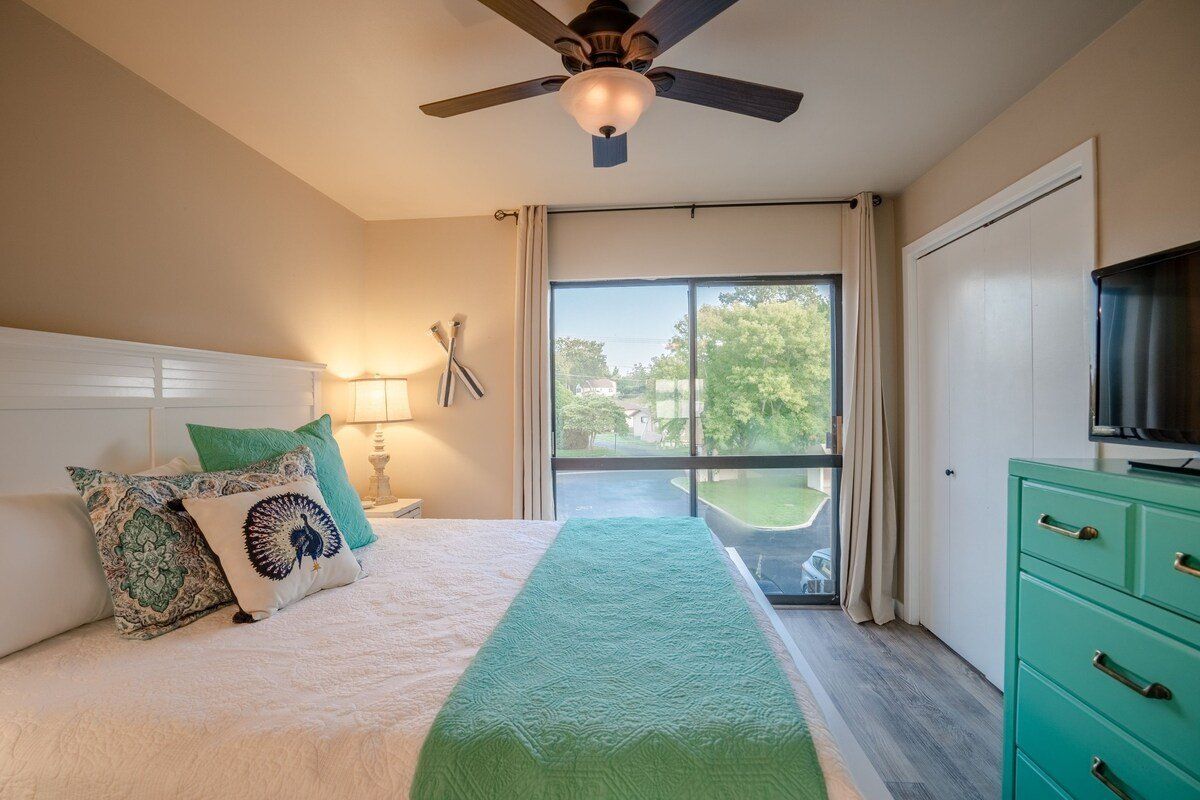 A bedroom with a bed , dresser , television and ceiling fan.