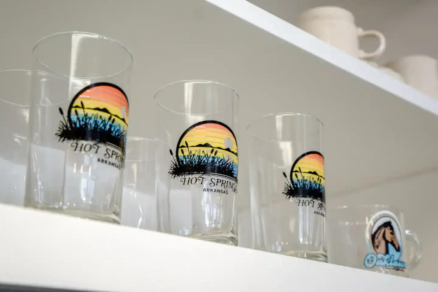 A row of glasses on a shelf with one that says sunset on it