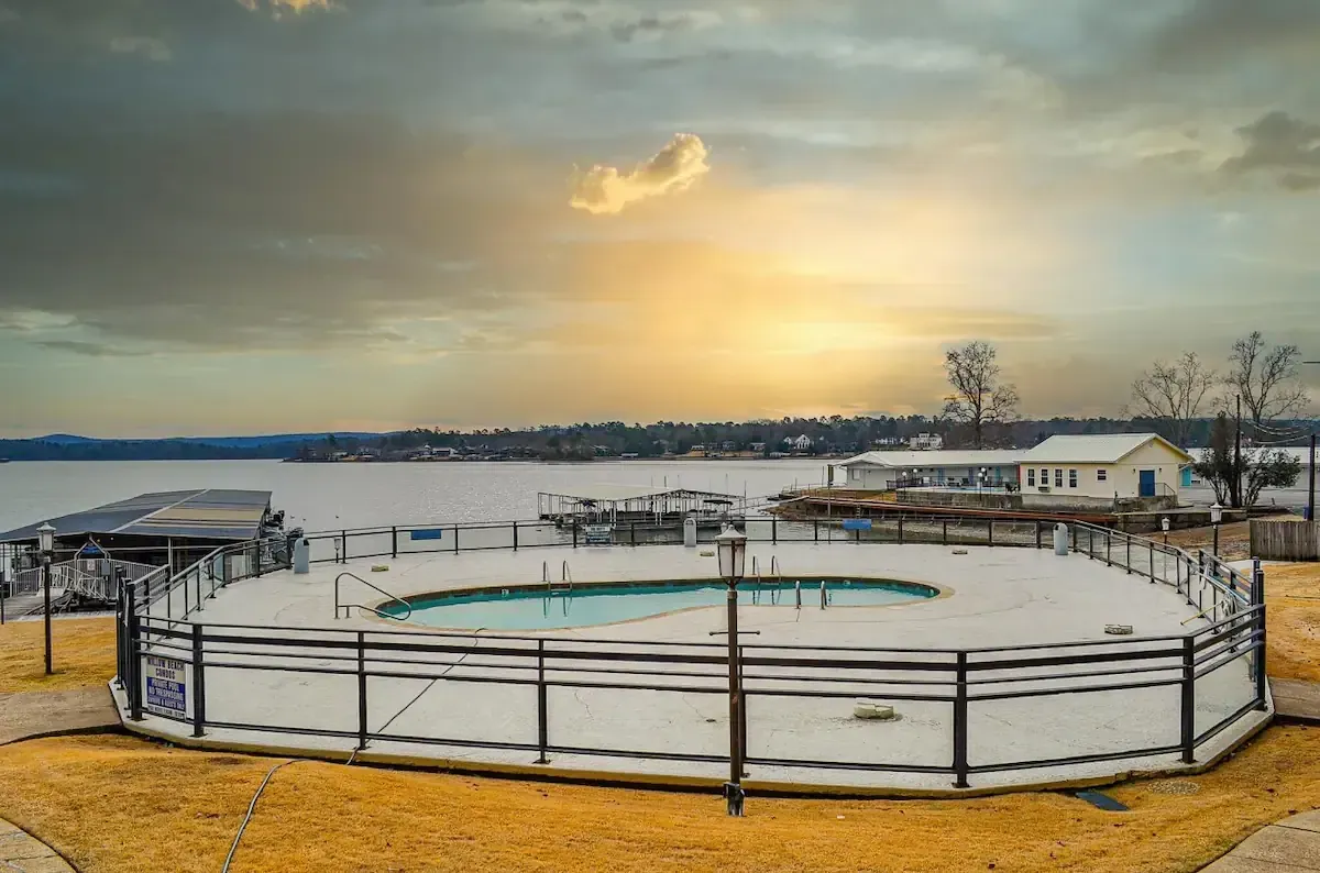 A large swimming pool surrounded by a fence next to a body of water.