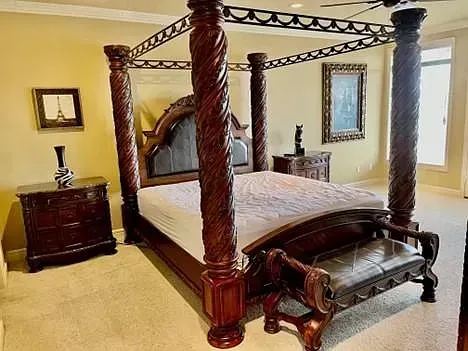 A bedroom with a canopy bed , nightstand , and bench.