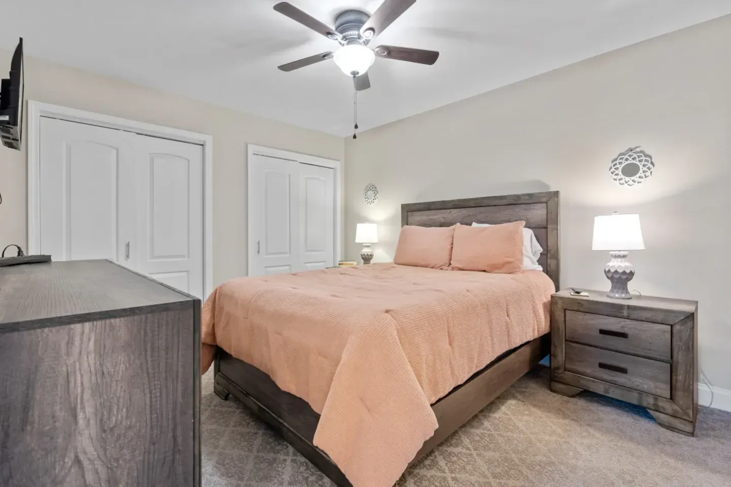 A bedroom with a king size bed , nightstand , dresser and ceiling fan.