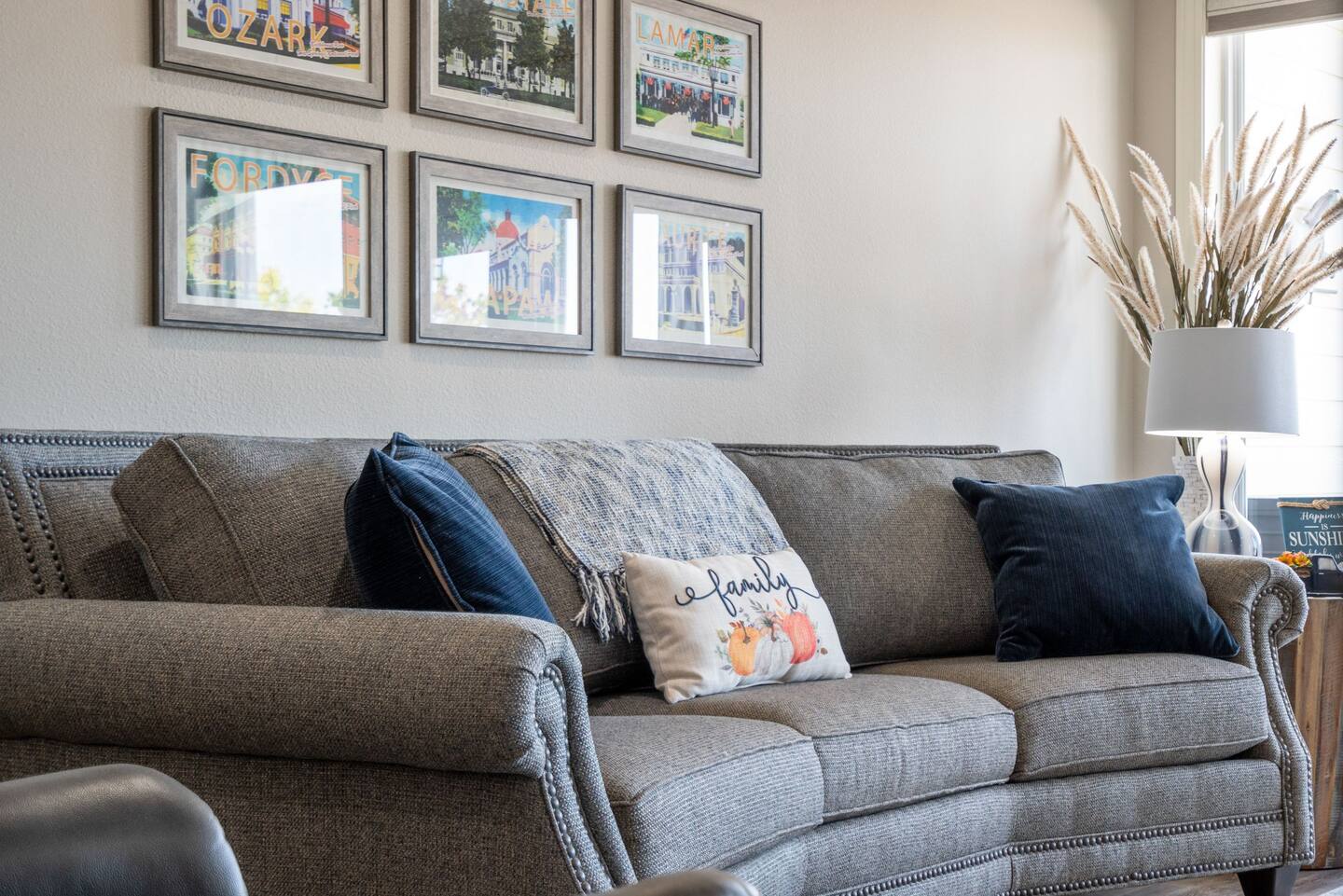 A living room with a couch , chairs , and pictures on the wall.