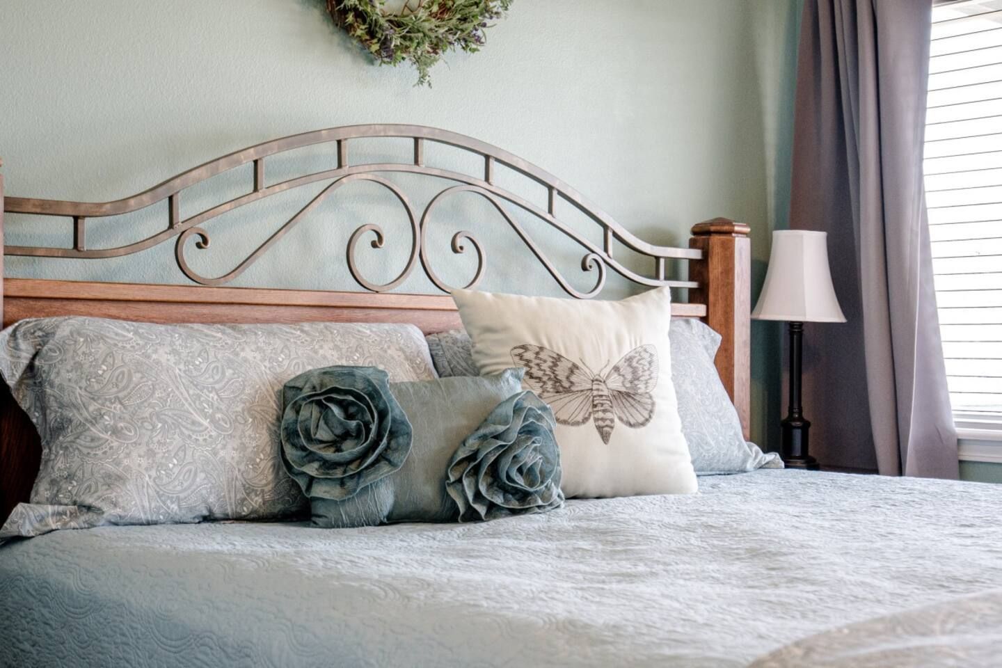A bed with a wrought iron headboard and pillows in a bedroom.