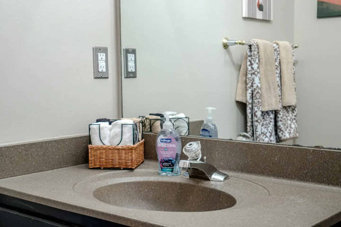 A bathroom with a sink , mirror and towels.