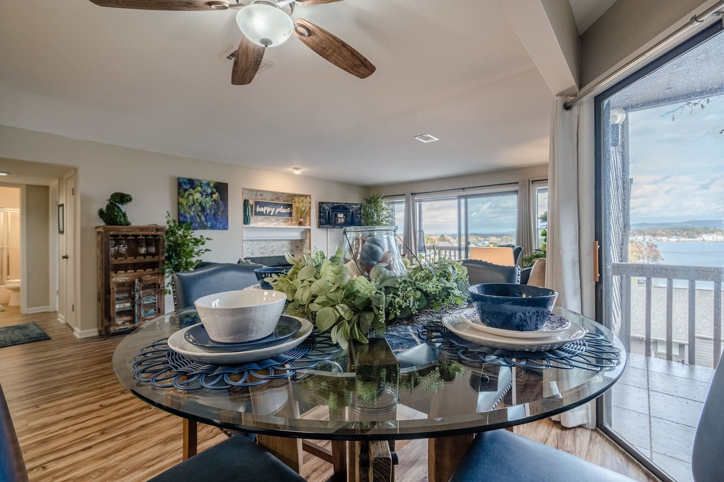 A dining room with a glass table and chairs and a ceiling fan.