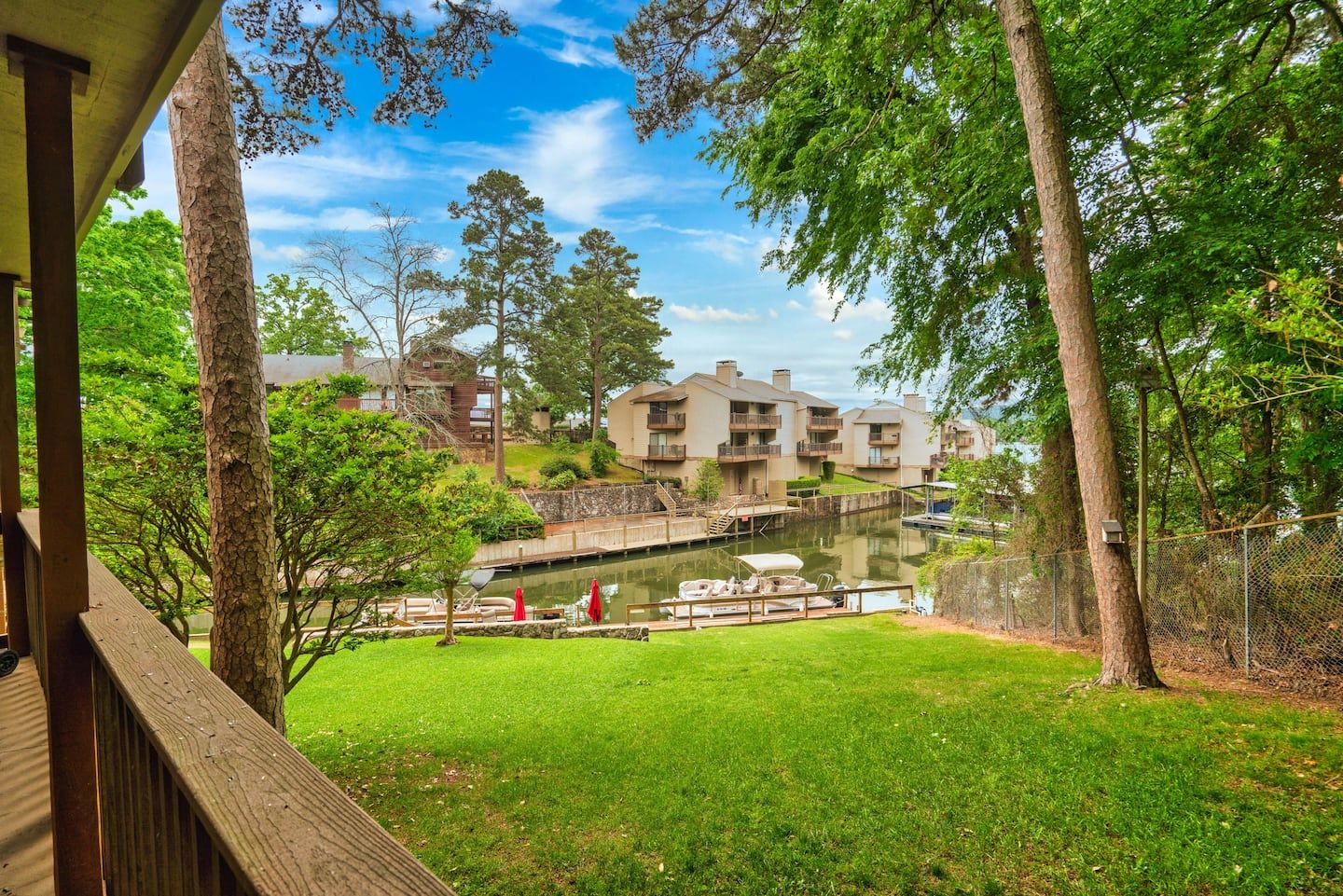 A view of a lake from a deck with a house in the background.