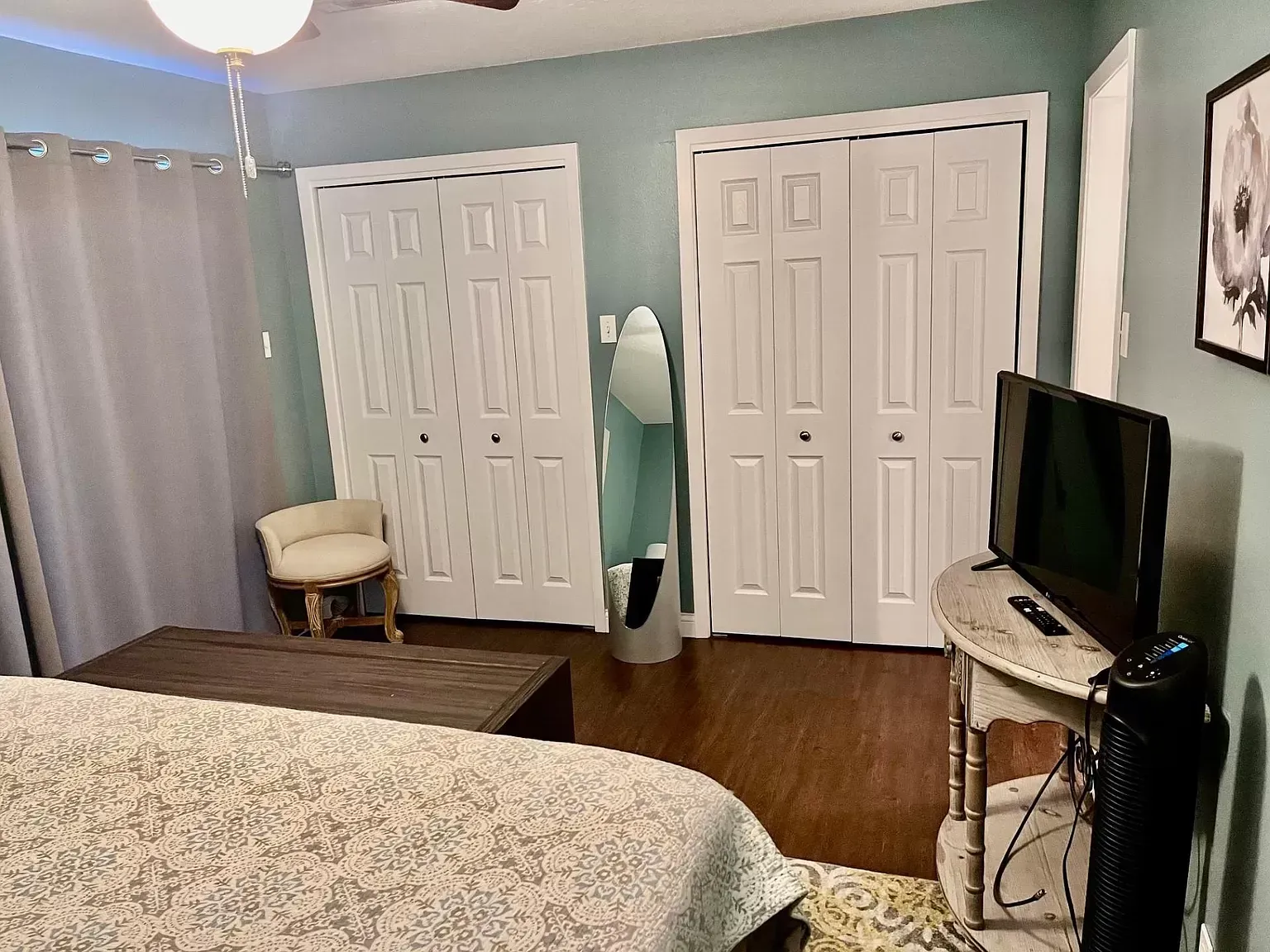 A bedroom with a bed , television , and closets.