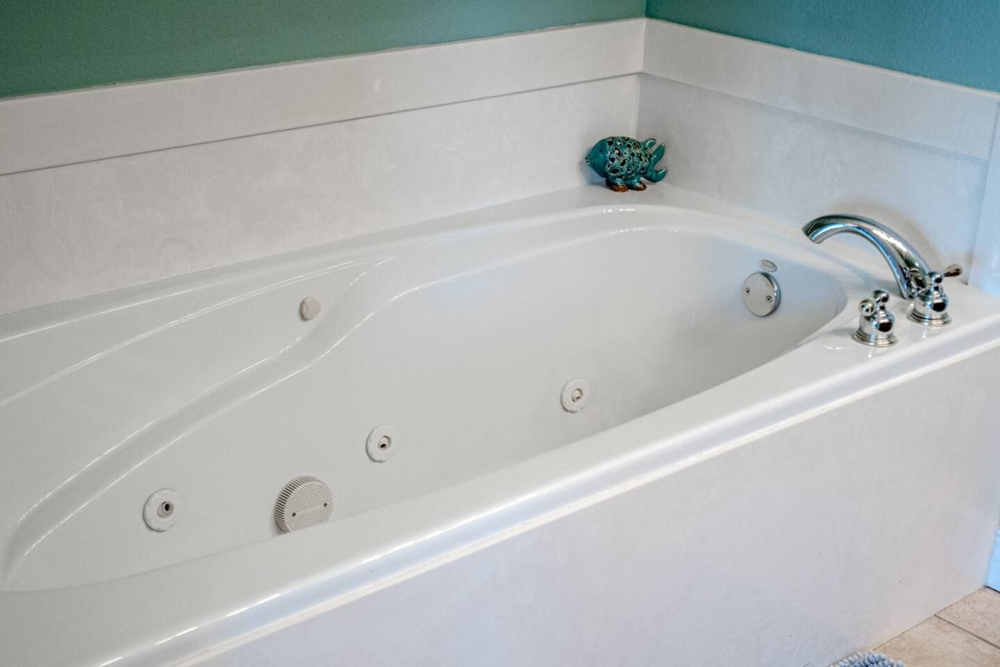 A white bathtub with a soap dish on top of it in a bathroom.