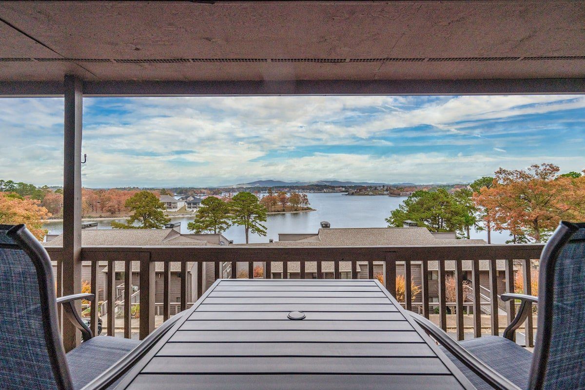 A balcony with a table and chairs overlooking a lake.