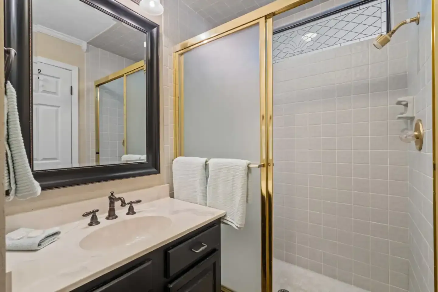 A bathroom with a sink , mirror , and walk in shower.
