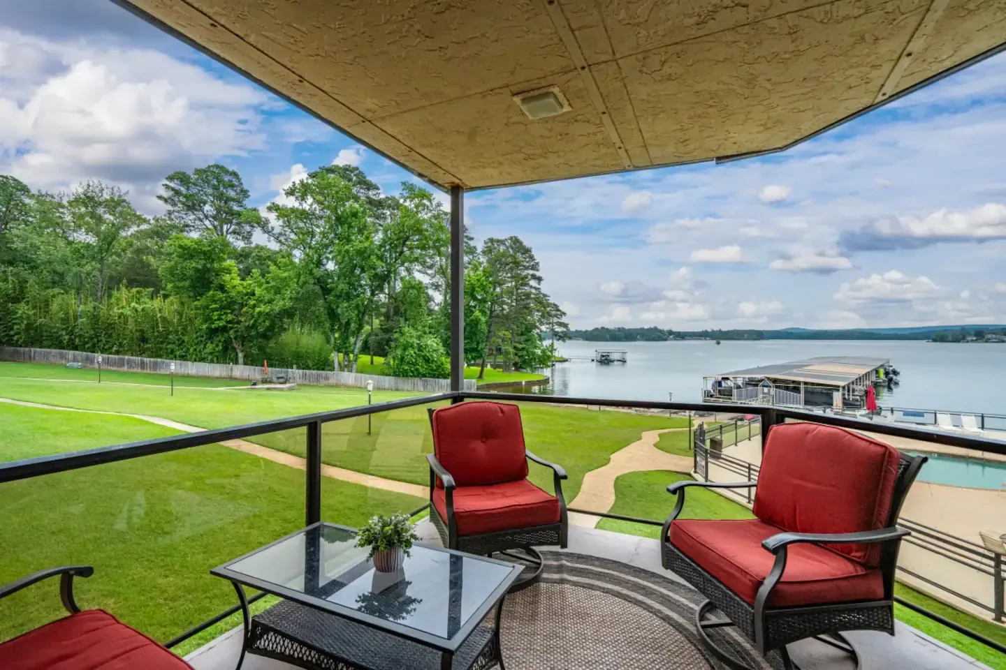 A balcony with chairs and a table overlooking a lake.
