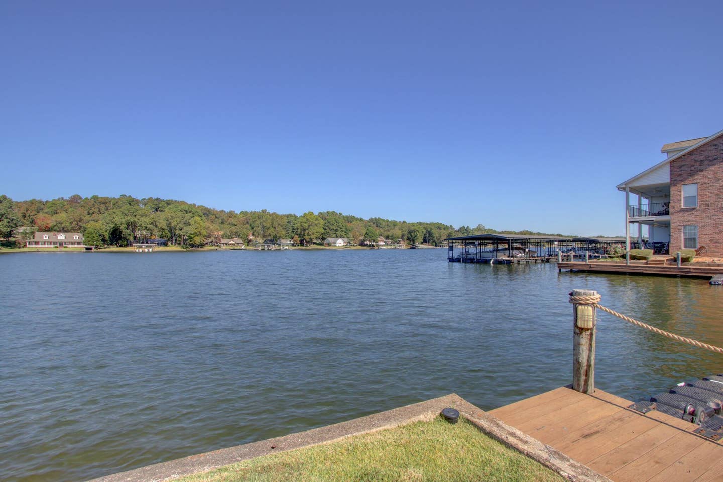 A large body of water with a dock in the foreground and a house in the background.