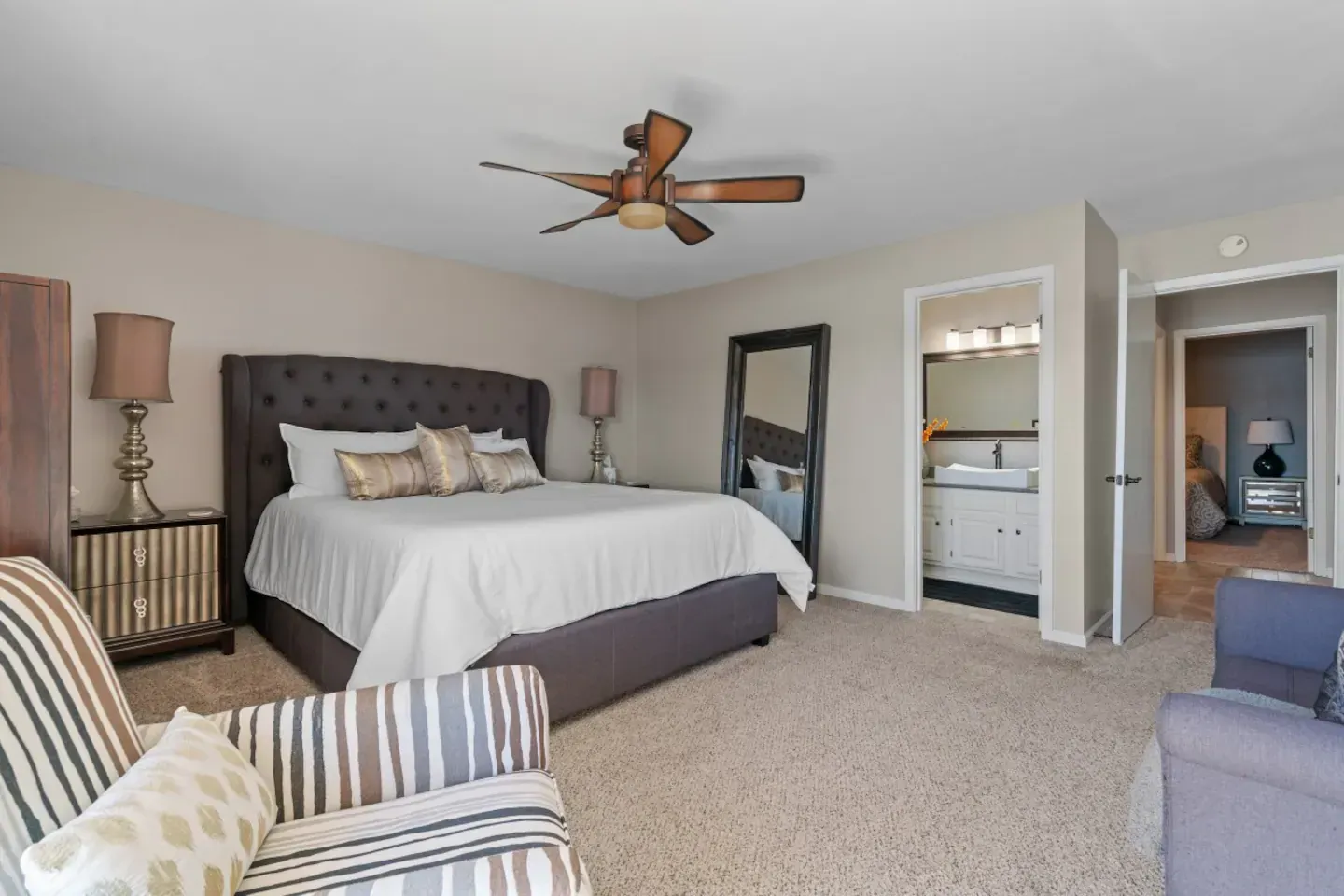 A bedroom with a king size bed , chair , and ceiling fan.