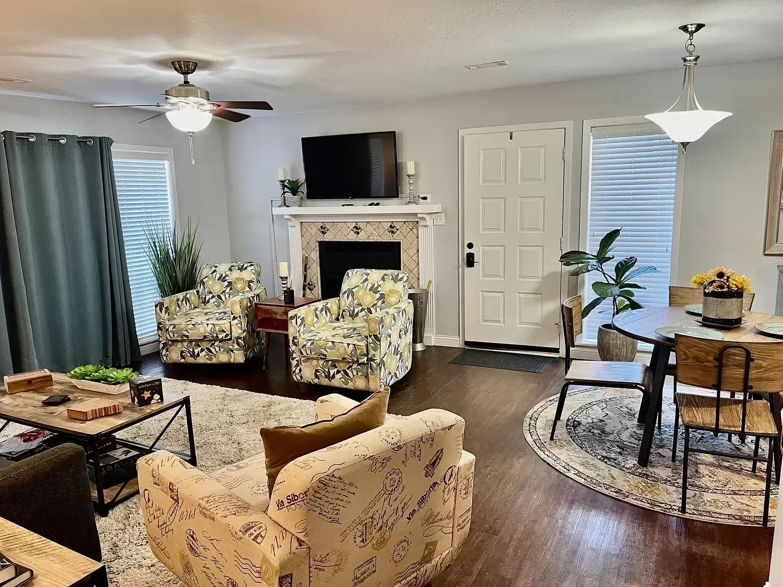 A living room with a couch , chairs , a table and a fireplace.
