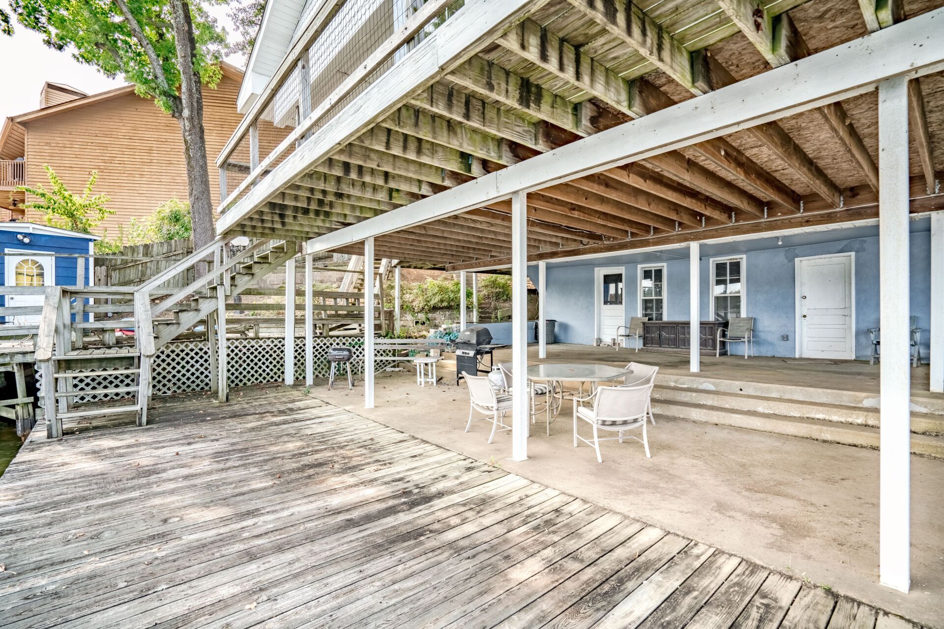 There is a large deck with tables and chairs underneath it.