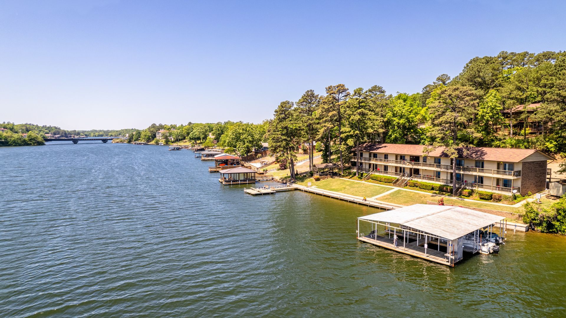 An aerial view of a lake with a dock and houses on the shore.