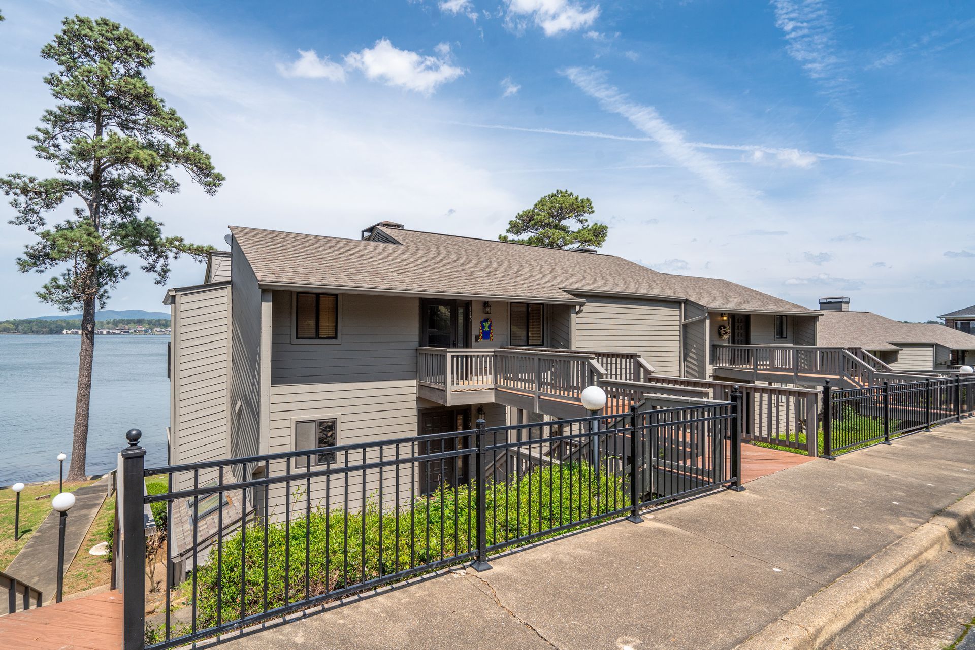 A large apartment building next to a lake with a fence around it.
