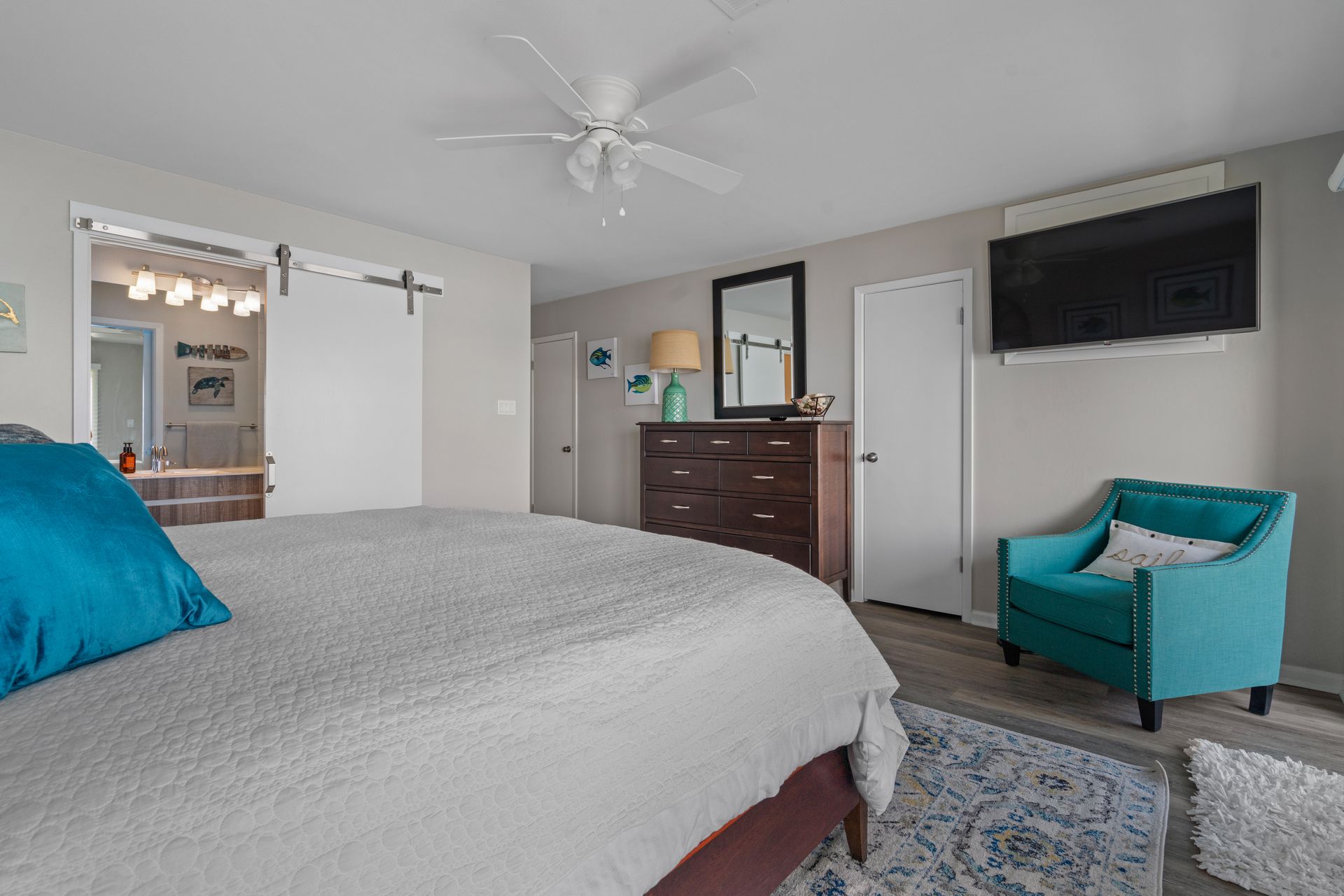 A bedroom with a bed , chair , dresser and television.