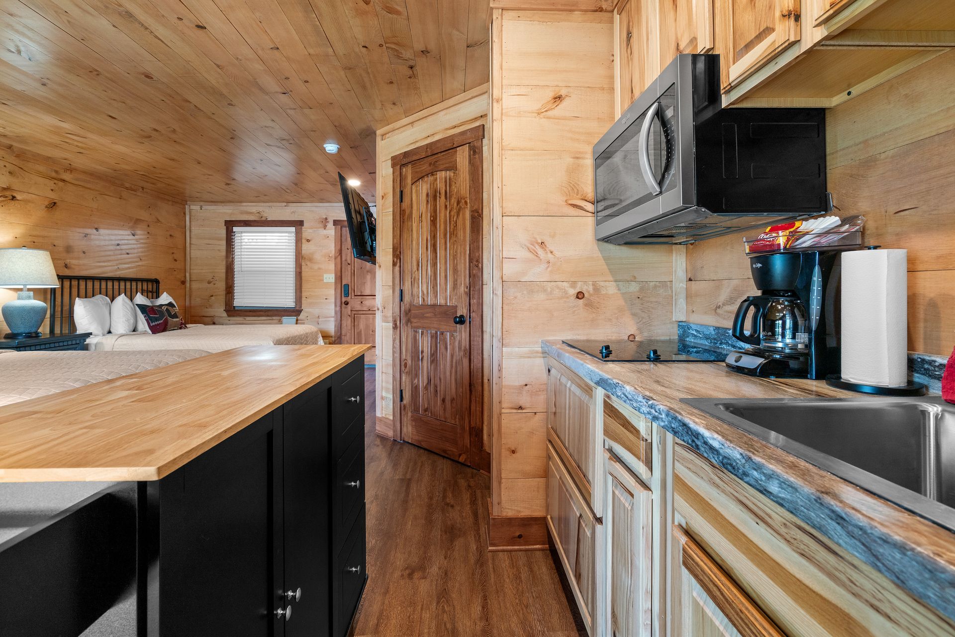 A kitchen in a cabin with a sink , microwave , and stove.