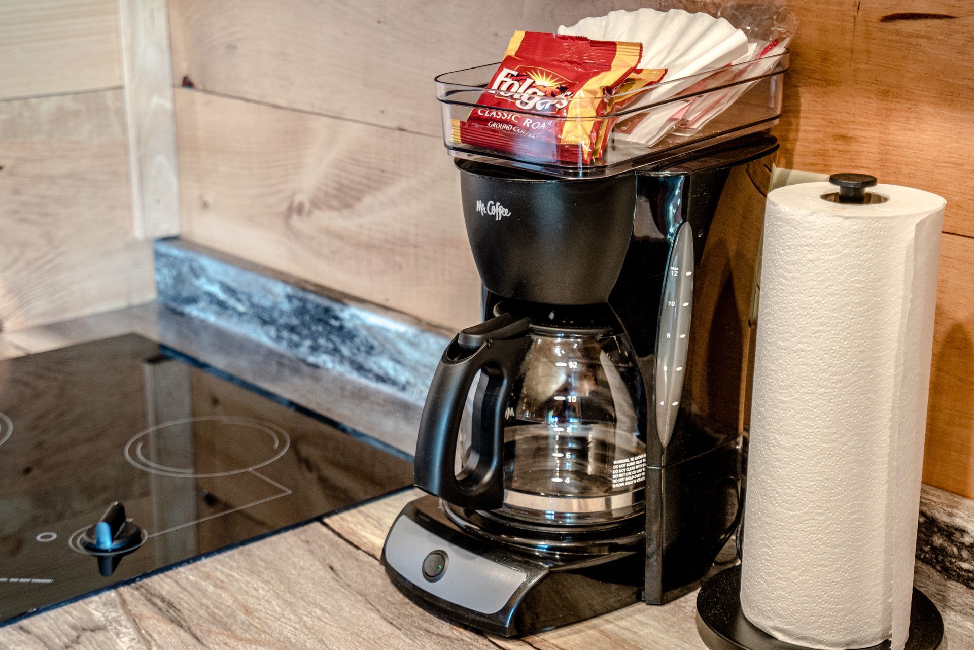 A coffee maker is sitting on a kitchen counter next to a paper towel holder.