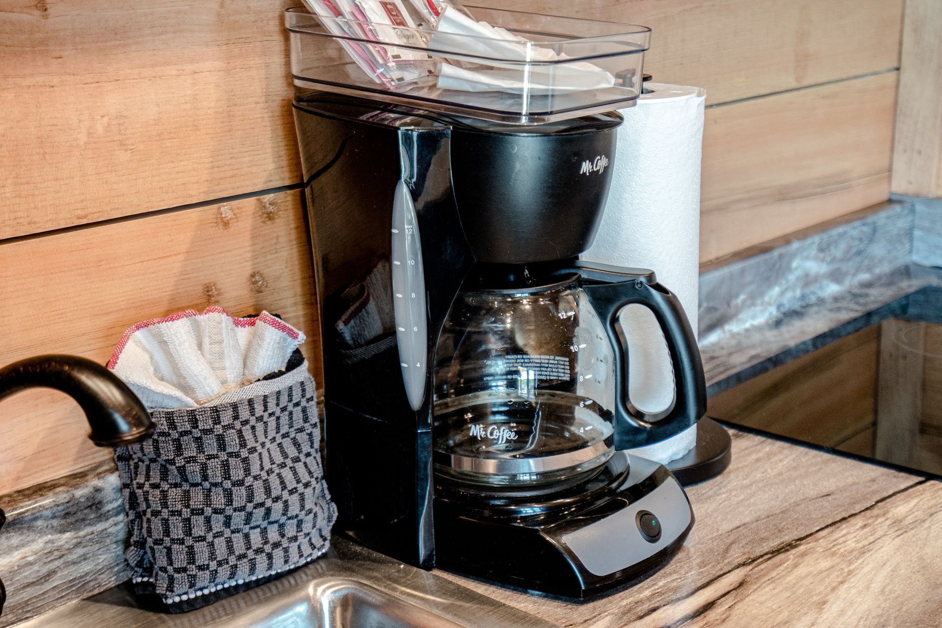 A coffee maker is sitting on a counter next to a sink.