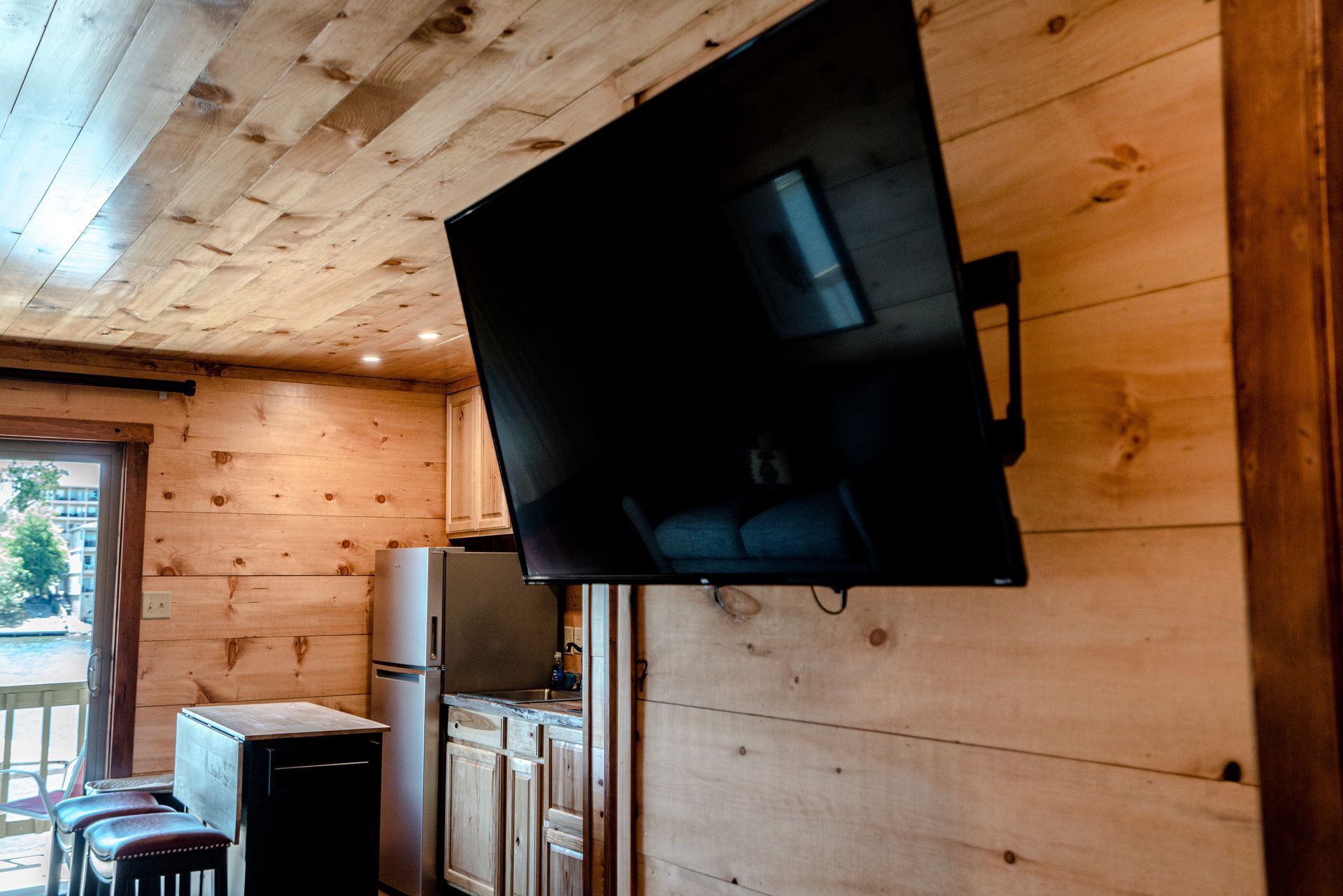 A flat screen tv is mounted on a wooden wall in a cabin.