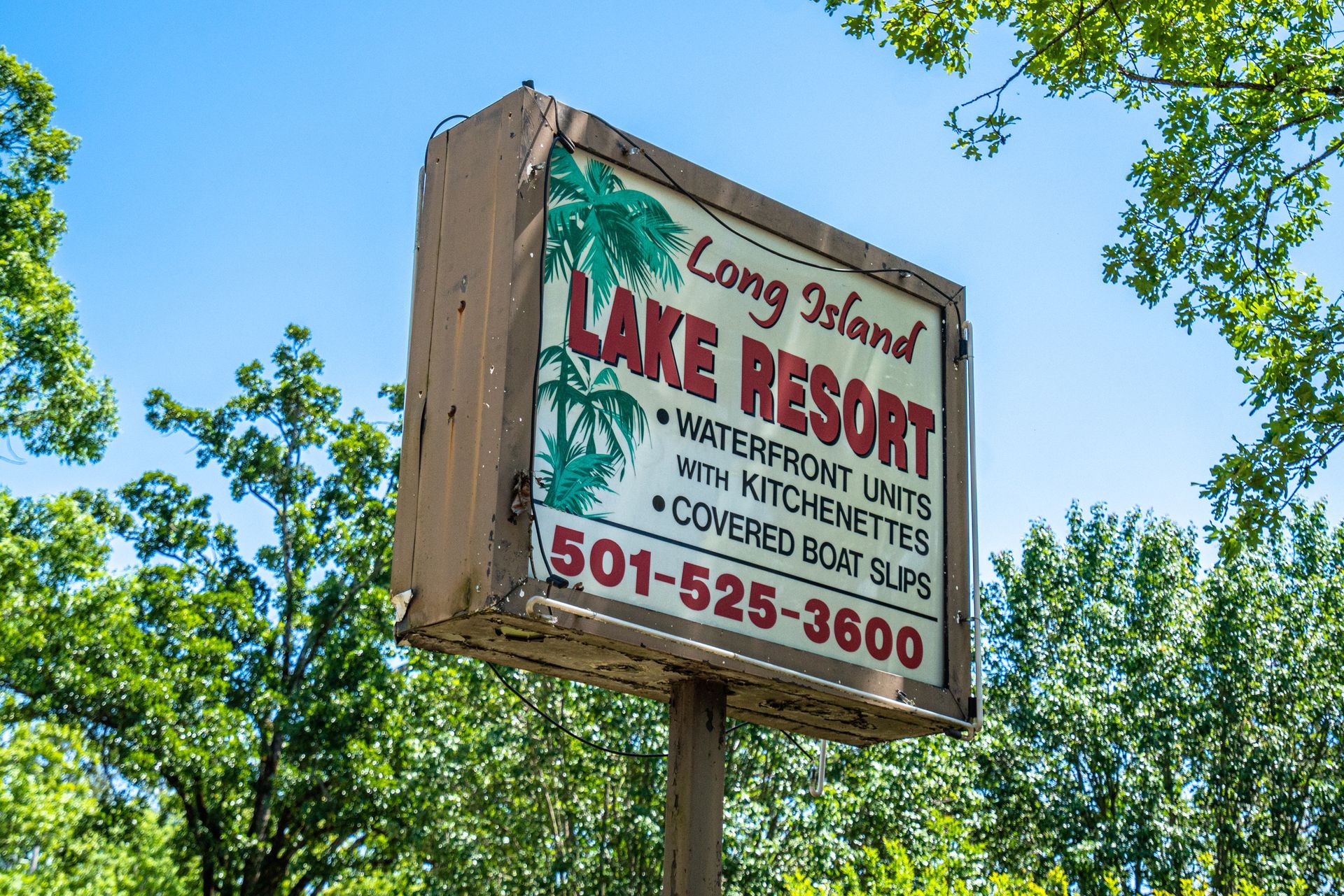 A sign for long island lake resort is surrounded by trees